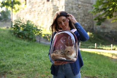 Photo of Woman with her cute cat in backpack carrier at park