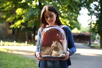 Photo of Woman with her cute cat in backpack carrier at park