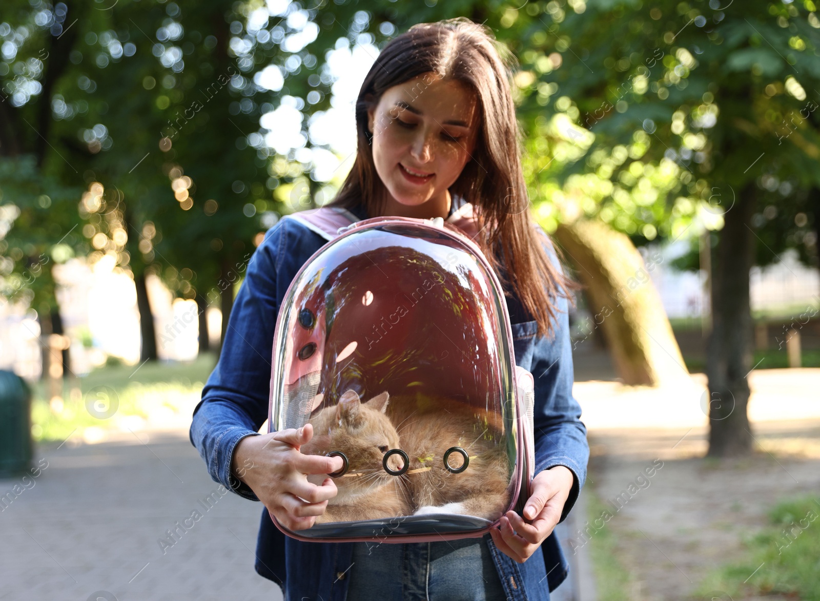 Photo of Woman with her cute cat in backpack carrier at park