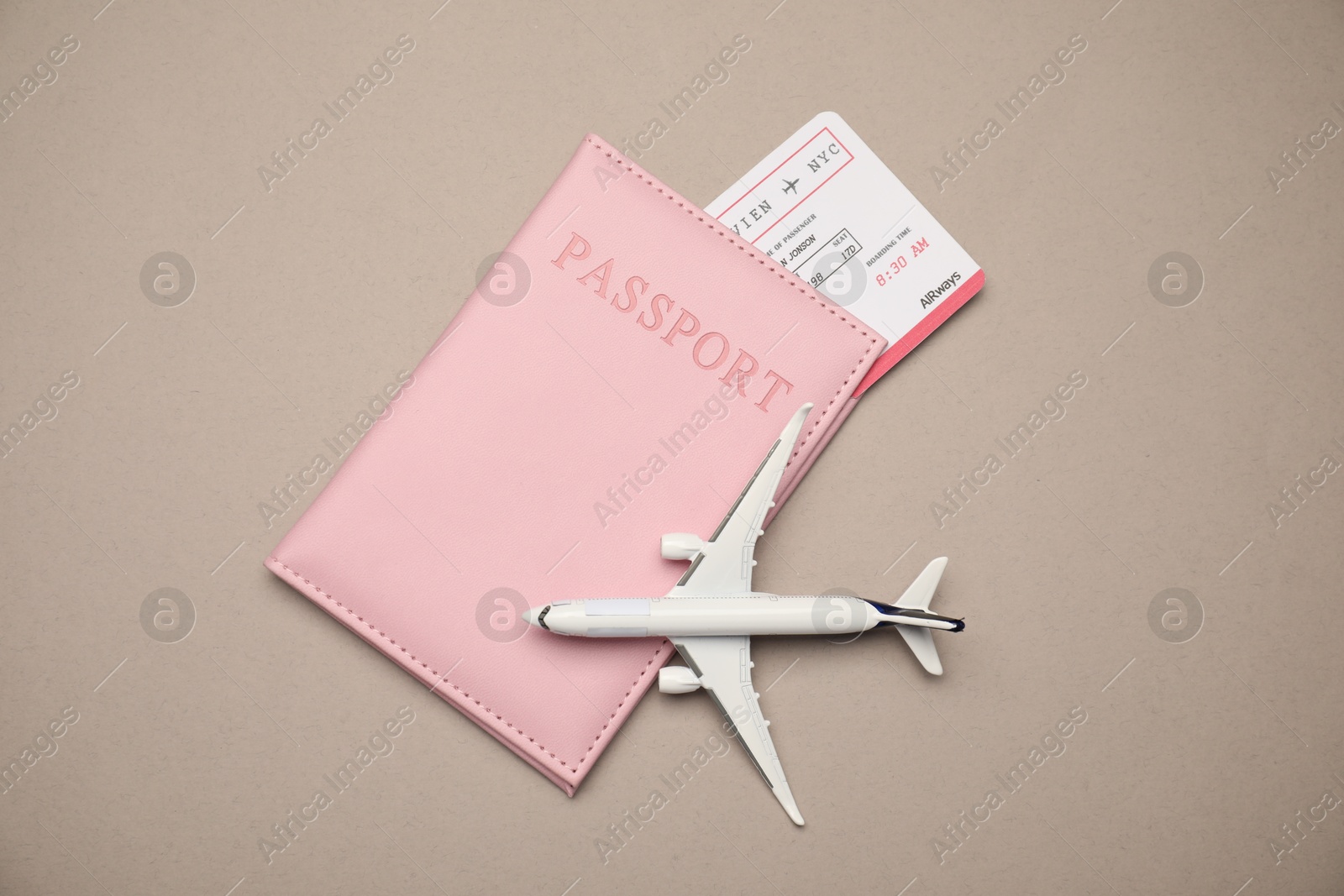 Photo of Airplane model, passport and flight ticket on beige background, flat lay