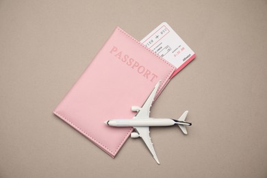 Photo of Airplane model, passport and flight ticket on beige background, flat lay