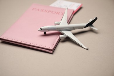 Photo of Airplane model, passport and flight ticket on beige background, closeup
