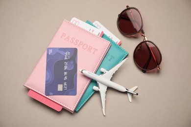 Photo of Airplane model, passports, flight tickets, credit card and sunglasses on beige background, flat lay