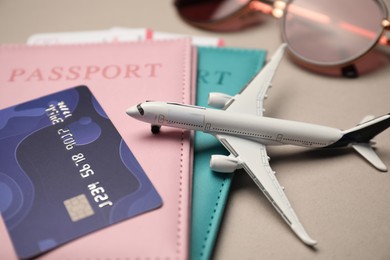 Photo of Airplane model, passports, flight tickets, credit card and sunglasses on beige background, closeup