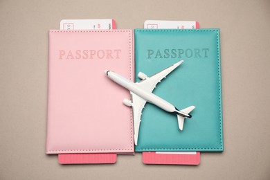 Photo of Airplane model, passports and flight tickets on beige background, flat lay