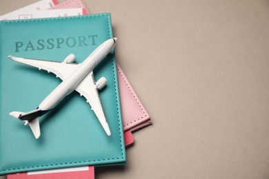Photo of Airplane model, passports and flight tickets on beige background, above view. Space for text