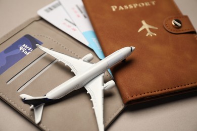 Photo of Airplane model, passport, flight tickets and credit card on beige background, closeup
