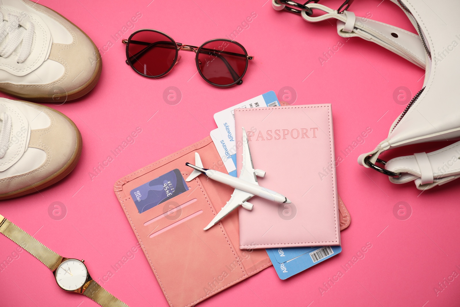 Photo of Airplane model, passport, flight tickets, credit card, and accessories on pink background, flat lay