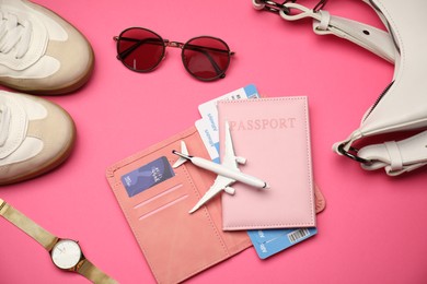 Photo of Airplane model, passport, flight tickets, credit card, and accessories on pink background, flat lay