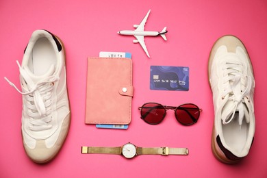 Photo of Airplane model, passport, flight ticket, credit card, and accessories on pink background, flat lay