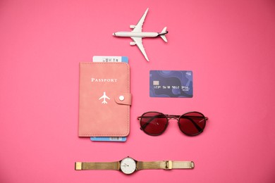 Photo of Airplane model, passport, flight ticket, credit card, and accessories on pink background, flat lay