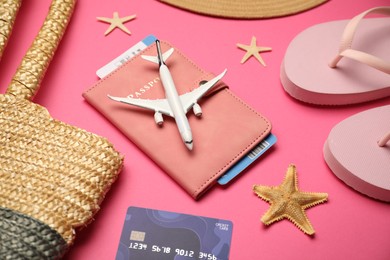 Photo of Airplane model, passport, flight ticket, credit card, and beach accessories on pink background, above view