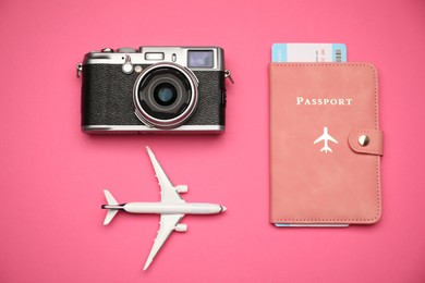Photo of Airplane model, passport, flight ticket and vintage photo camera on pink background, flat lay