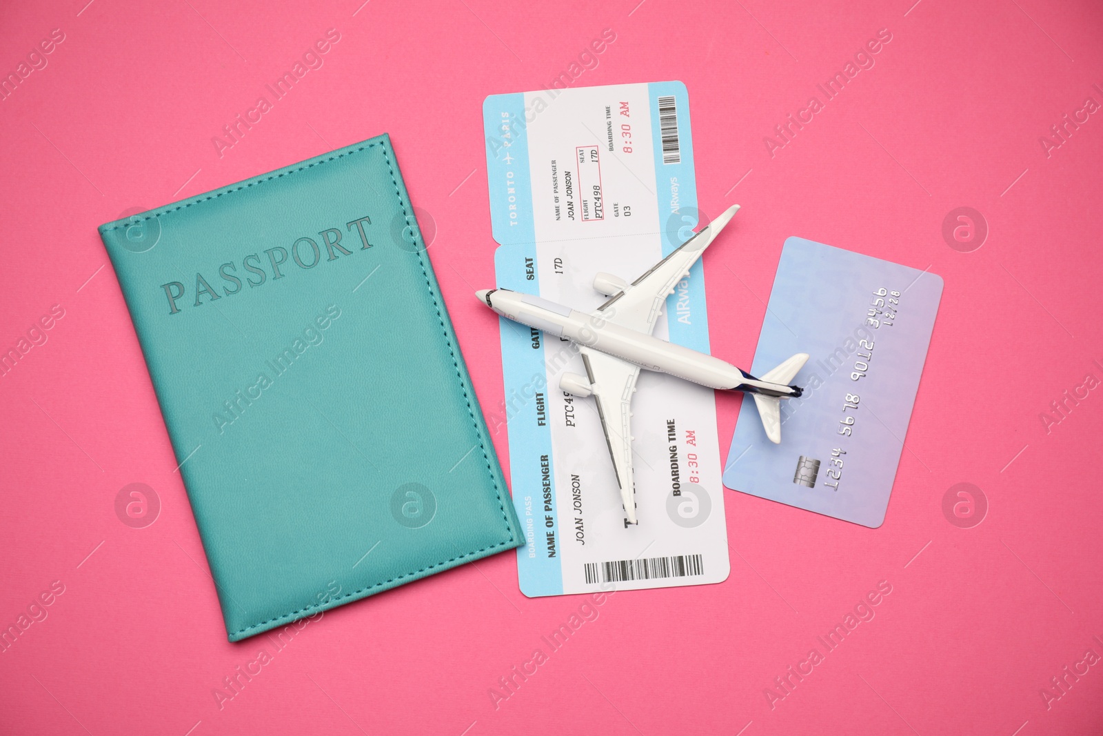 Airplane model, passport, flight ticket and credit card on pink background, flat lay Photo of Airplane model, passport, flight ticket and credit card on pink background, flat lay