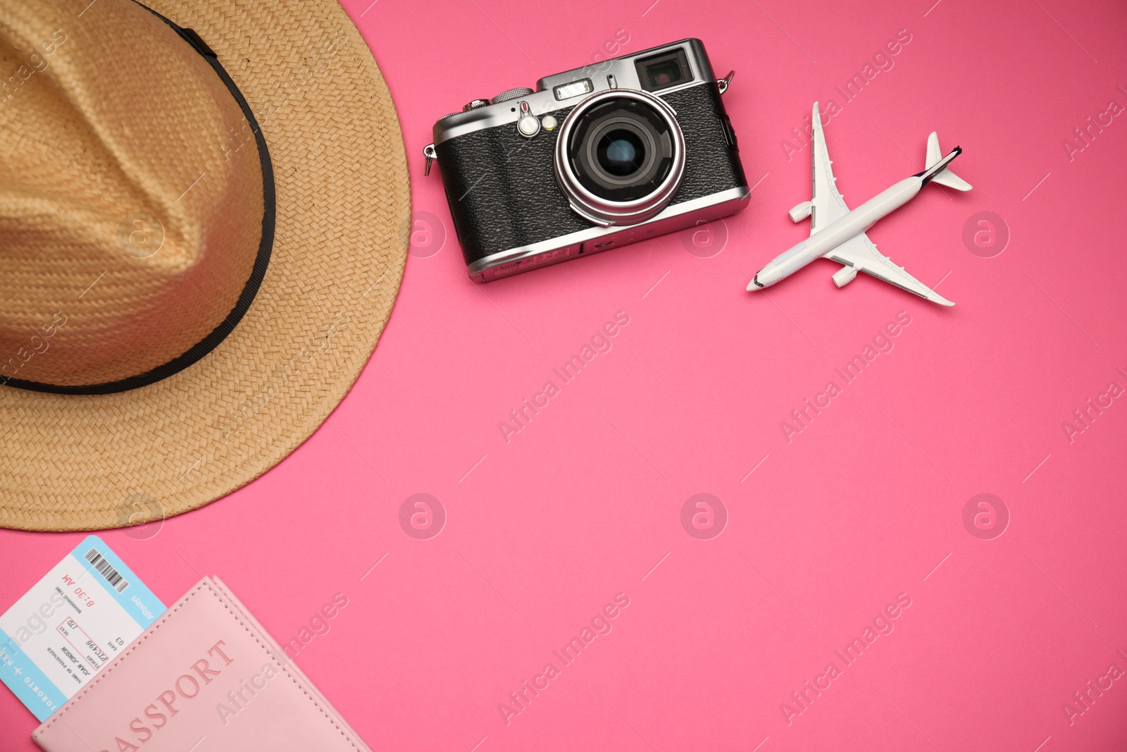 Photo of Airplane model, passport, flight ticket, vintage photo camera and hat on pink background, flat lay. Space for text