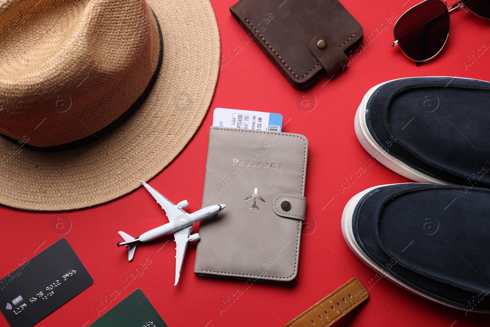 Airplane model, credit cards, passport, flight ticket, shoes and accessories on red background, flat lay Photo of Airplane model, credit cards, passport, flight ticket, shoes and accessories on red background, flat lay