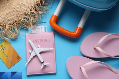 Photo of Airplane model, passport, flight ticket, credit cards and accessories on light blue background, flat lay