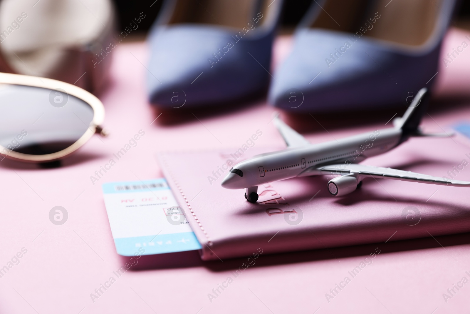 Airplane model, passport, flight ticket and shoes on pink background, closeup Photo of Airplane model, passport, flight ticket and shoes on pink background, closeup