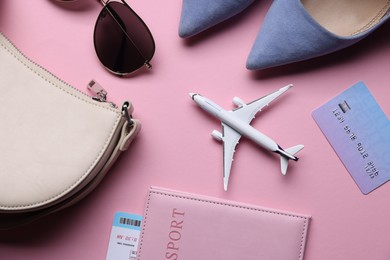 Photo of Airplane model, passport, flight ticket, credit card, shoes and accessories on pink background, flat lay