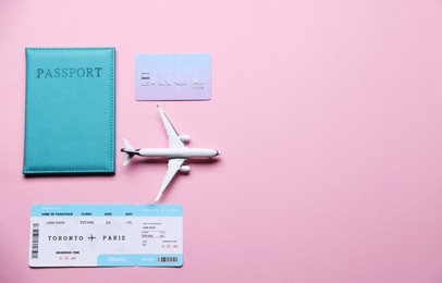 Photo of Airplane model, flight ticket, passport and credit card on pink background, flat lay. Space for text