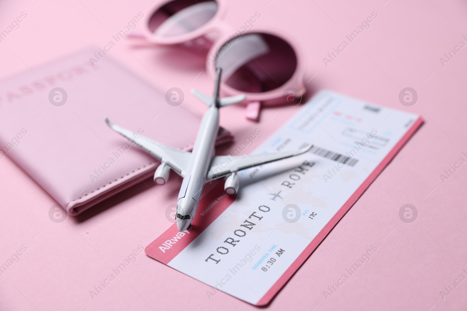 Airplane model, flight ticket, passport and sunglasses on pink background, closeup Photo of Airplane model, flight ticket, passport and sunglasses on pink background, closeup