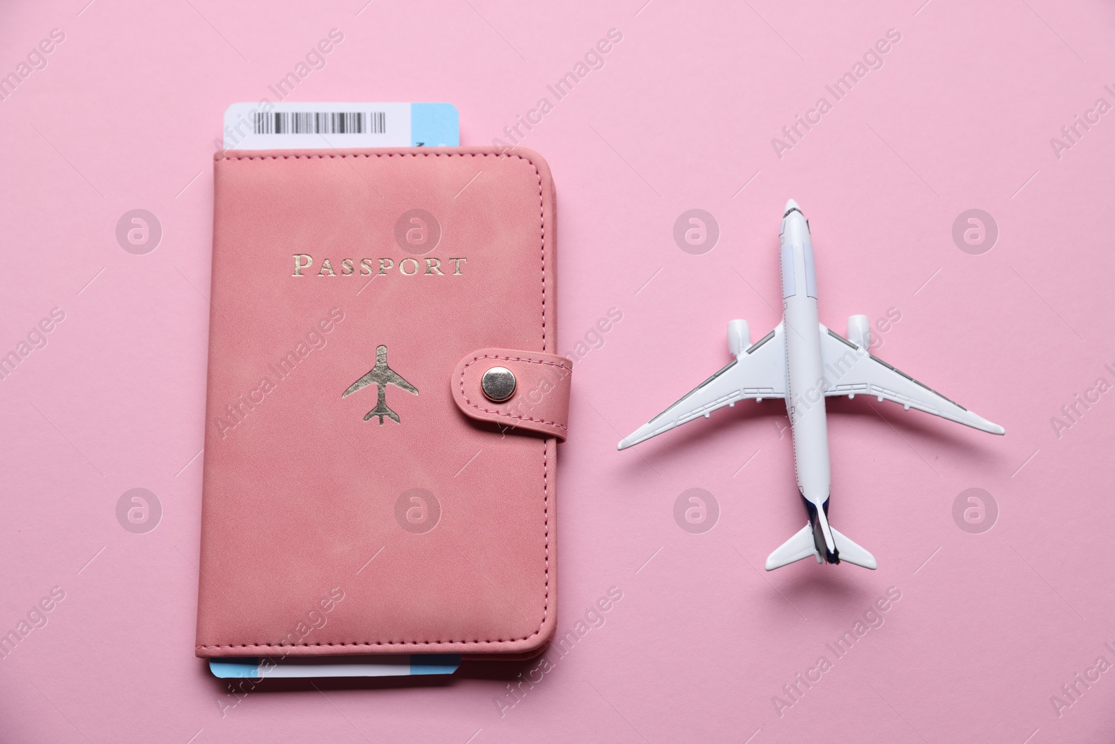Photo of Airplane model, flight ticket and passport on pink background, flat lay
