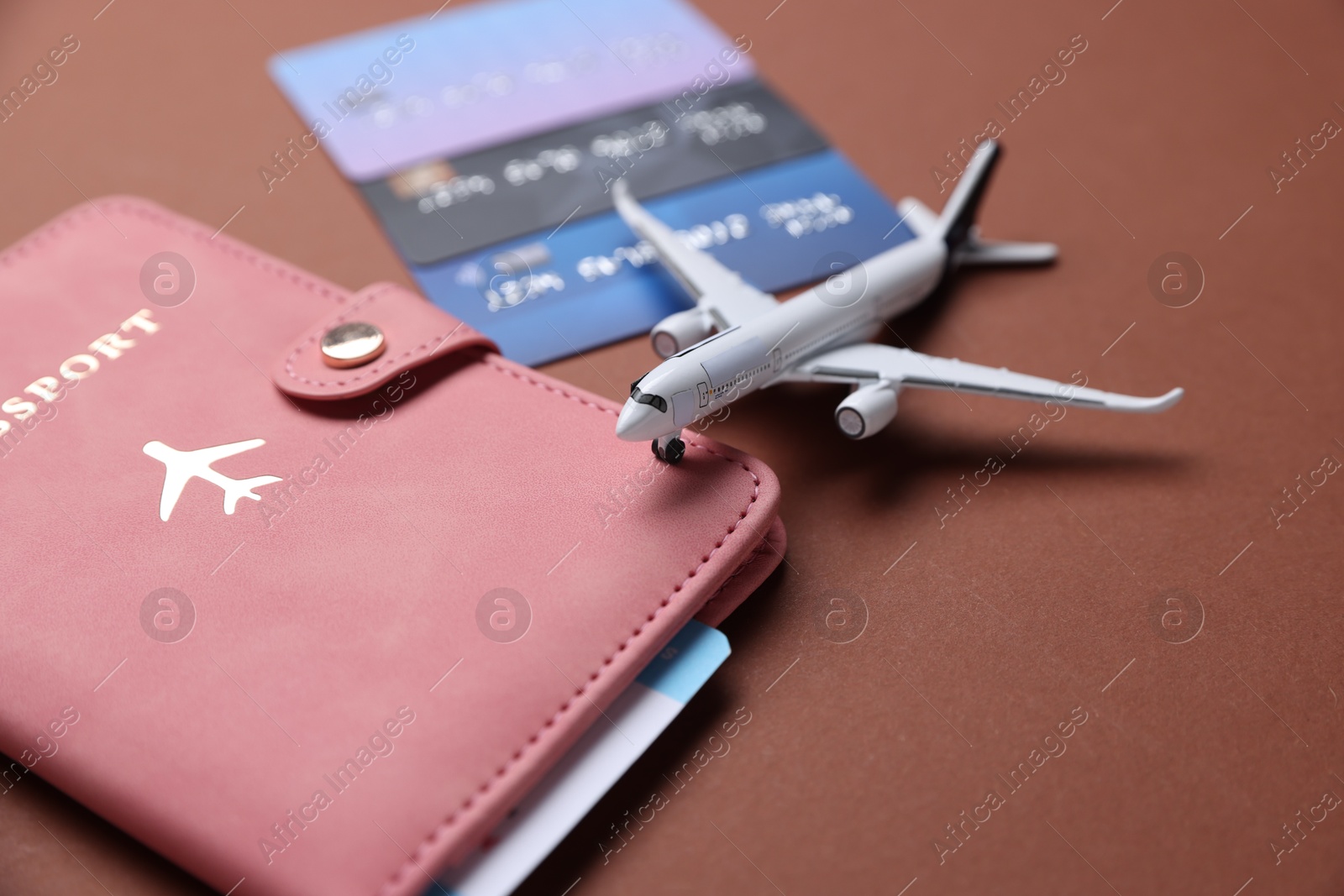 Airplane model, flight ticket, passport and credit cards on brown background, closeup Photo of Airplane model, flight ticket, passport and credit cards on brown background, closeup