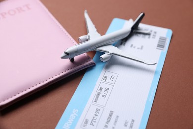 Photo of Airplane model, flight ticket and passport on brown background, closeup