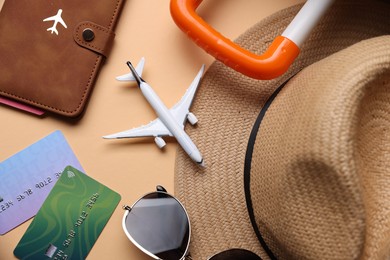 Photo of Airplane model, passport, credit cards and accessories on beige background, flat lay