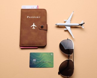 Photo of Airplane model, passport, flight ticket, sunglasses and credit card on beige background, flat lay