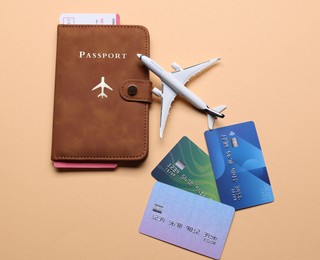 Photo of Airplane model, passport, flight ticket and credit cards on beige background, flat lay
