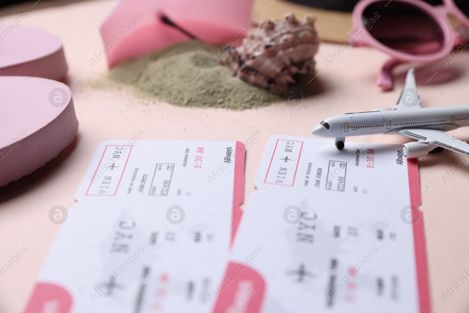 Flight tickets, airplane model, sand and beach accessories on beige background, closeup Photo of Flight tickets, airplane model, sand and beach accessories on beige background, closeup