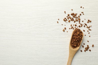 Photo of Spoon with granulated instant coffee on white wooden table, top view. Space for text