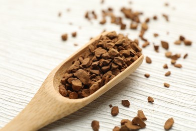 Photo of Spoon with granulated instant coffee on white wooden table, closeup