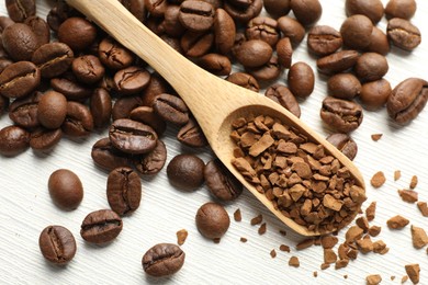 Photo of Spoon with granulated instant coffee and beans on white wooden table, above view