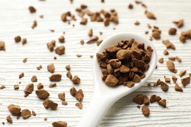 Photo of Spoon with granulated instant coffee on white wooden table, closeup