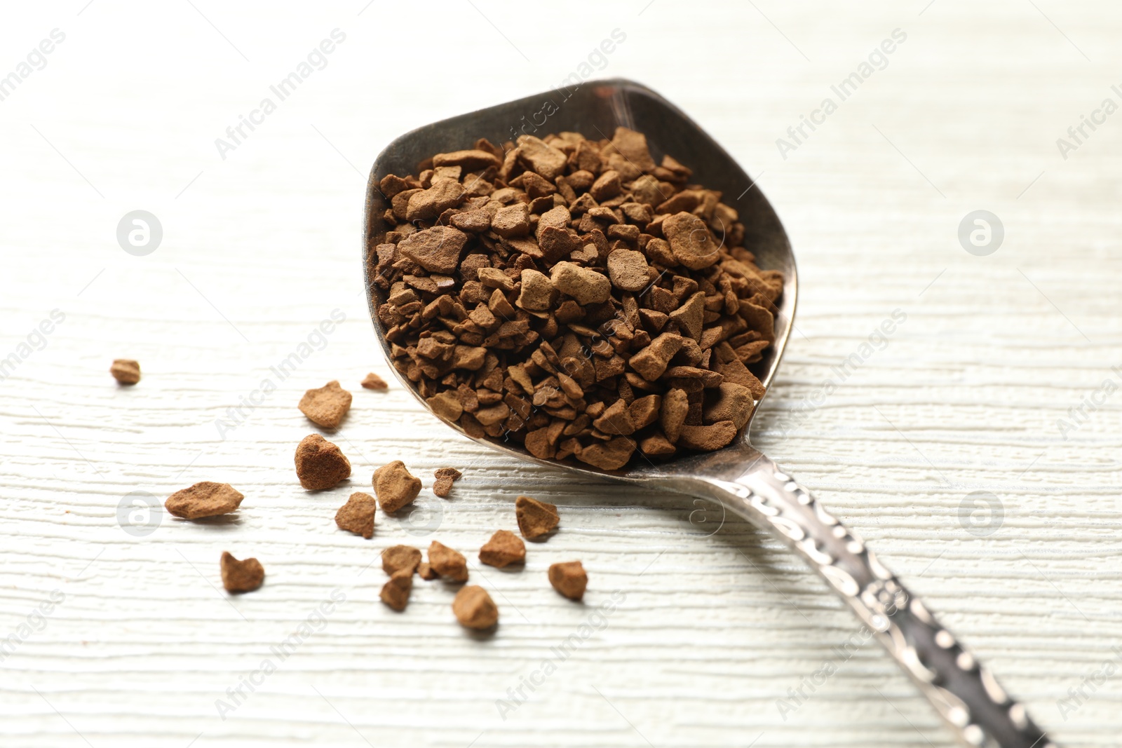 Spoon with granulated instant coffee on white wooden table, closeup Photo of Spoon with granulated instant coffee on white wooden table, closeup