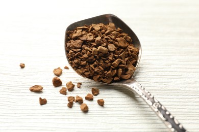 Photo of Spoon with granulated instant coffee on white wooden table, closeup