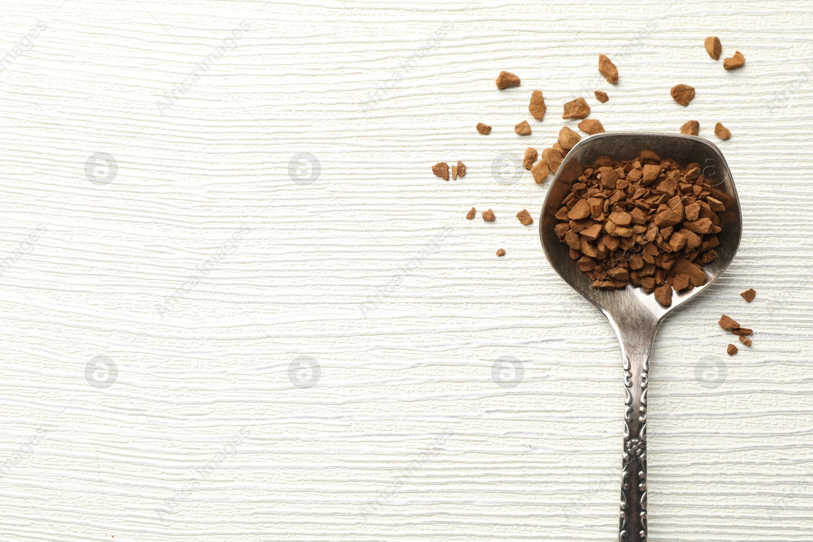 Photo of Spoon with granulated instant coffee on white wooden table, top view. Space for text
