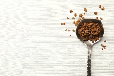 Photo of Spoon with granulated instant coffee on white wooden table, top view. Space for text