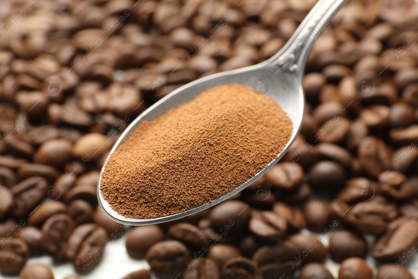 Photo of Spoon with instant coffee powder and beans, closeup