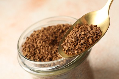 Photo of Spoon with granulated instant coffee and jar on light table, closeup
