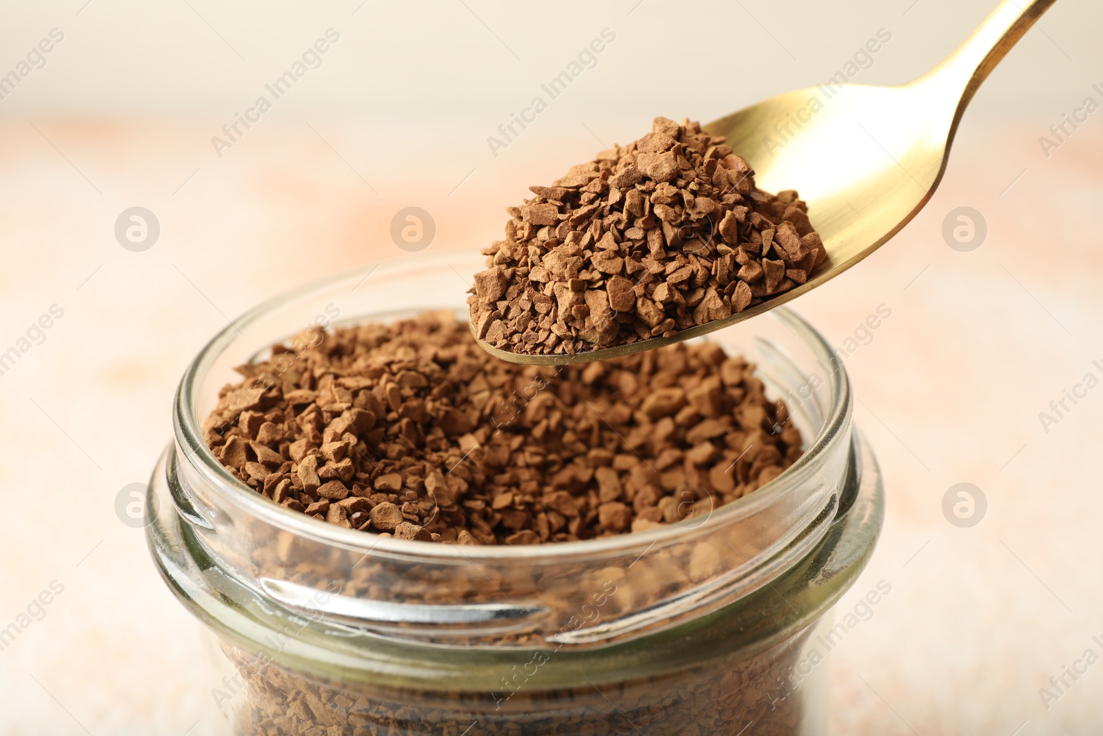 Taking granulated instant coffee from jar with spoon on blurred light background, closeup Photo of Taking granulated instant coffee from jar with spoon on blurred light background, closeup