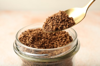 Photo of Taking granulated instant coffee from jar with spoon on blurred light background, closeup