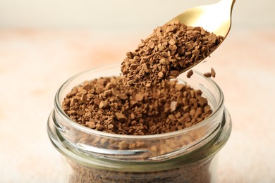 Photo of Taking granulated instant coffee from jar with spoon on blurred light background, closeup