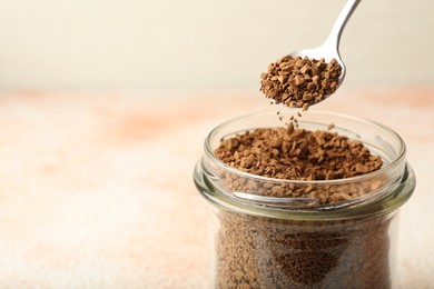 Photo of Taking granulated instant coffee from jar with spoon at light table, closeup. Space for text