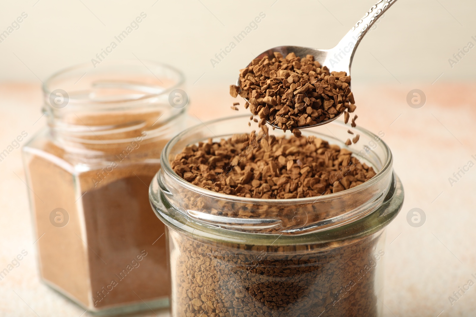 Taking granulated instant coffee from jar with spoon at light table, closeup Photo of Taking granulated instant coffee from jar with spoon at light table, closeup
