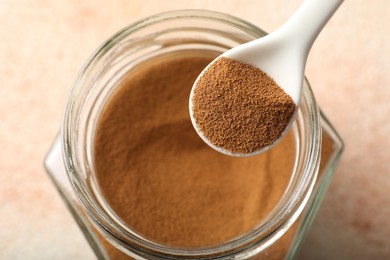Photo of Spoon with instant coffee powder and jar on light table, above view