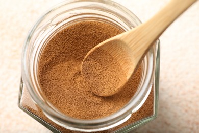 Photo of Taking instant coffee powder from jar with spoon at light table, closeup