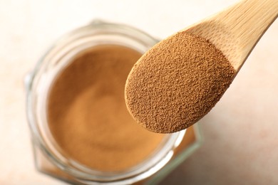 Photo of Spoon with instant coffee powder and jar on light table, top view